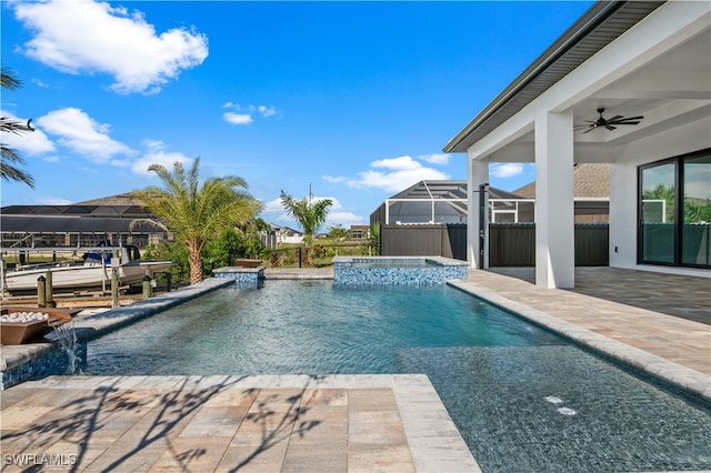 view of pool featuring an in ground hot tub, pool water feature, a patio area, glass enclosure, and ceiling fan