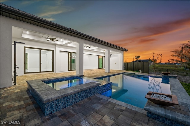 pool at dusk with an in ground hot tub, ceiling fan, and a patio