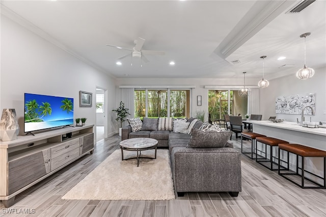 living room featuring ornamental molding, ceiling fan with notable chandelier, and light hardwood / wood-style flooring