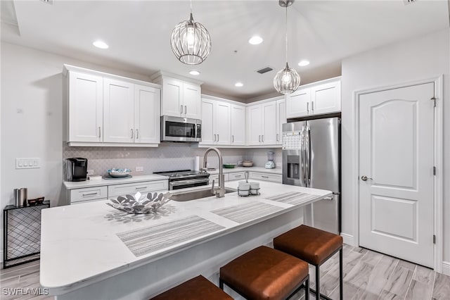 kitchen with decorative light fixtures, stainless steel appliances, sink, and white cabinetry