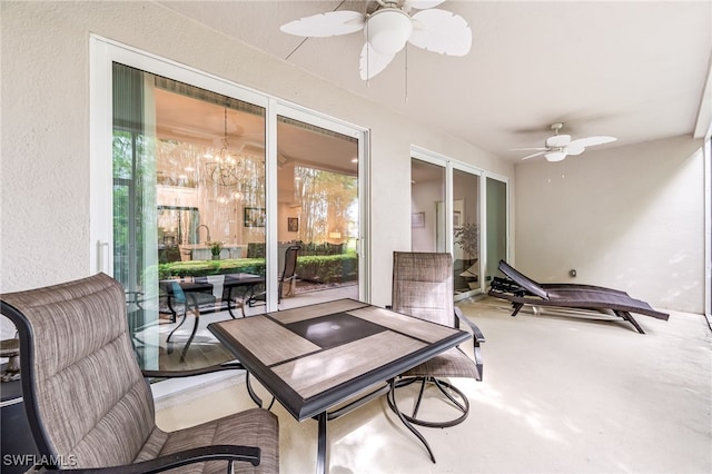 sunroom featuring ceiling fan with notable chandelier