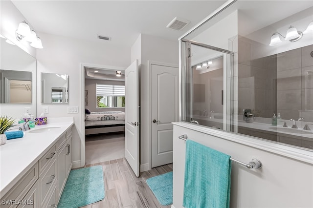 bathroom featuring hardwood / wood-style floors, a shower with shower door, and vanity