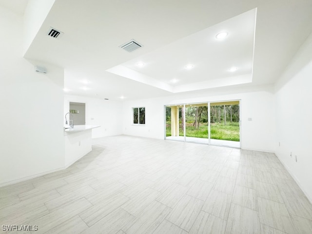 unfurnished living room featuring sink and a tray ceiling