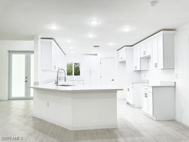 kitchen featuring sink, white cabinetry, kitchen peninsula, and french doors