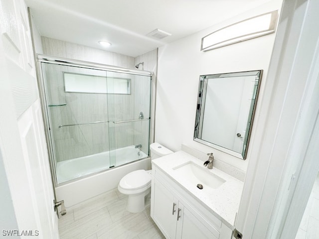 full bathroom featuring combined bath / shower with glass door, toilet, and vanity