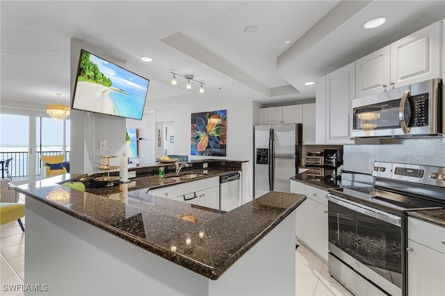 kitchen featuring stainless steel appliances, dark stone countertops, sink, a center island, and white cabinets