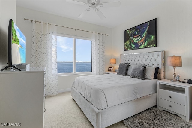 carpeted bedroom featuring a water view and ceiling fan