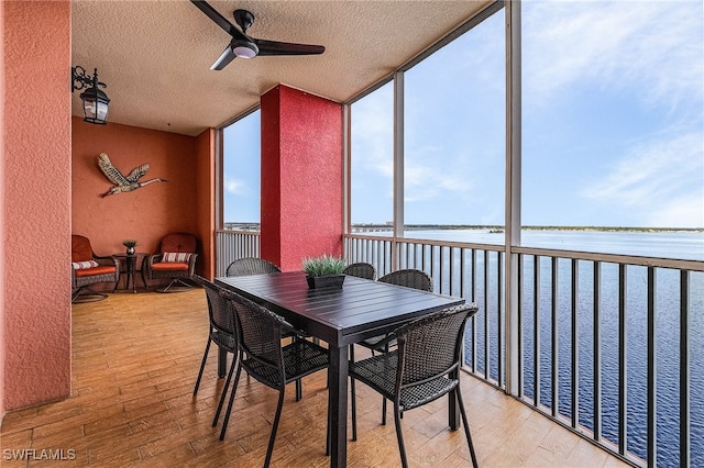 sunroom / solarium featuring a water view and ceiling fan