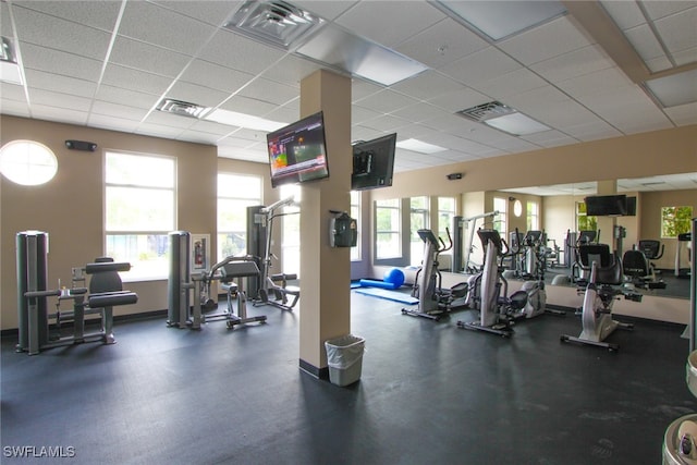 exercise room with a drop ceiling and a healthy amount of sunlight