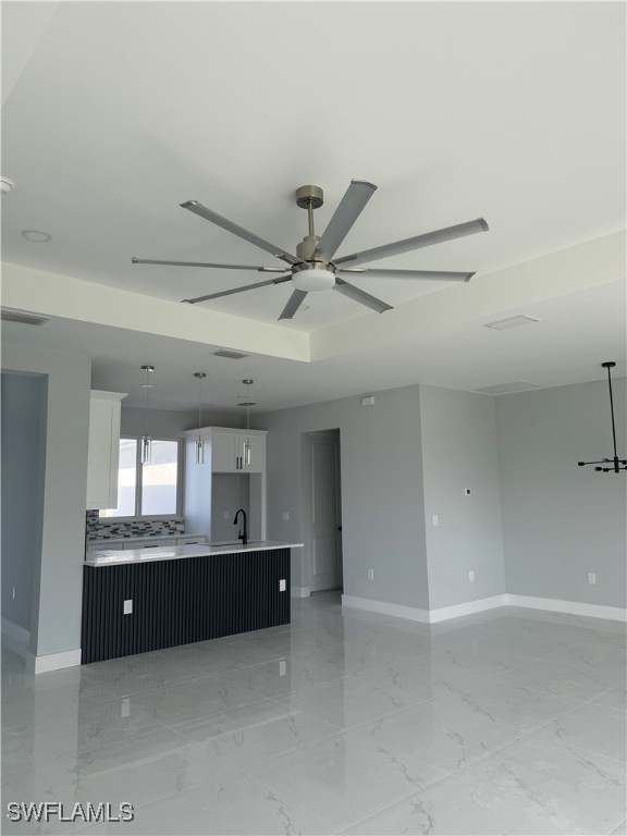 kitchen with tasteful backsplash, sink, white cabinets, and ceiling fan