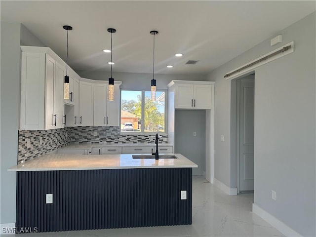 kitchen featuring sink, white cabinetry, tasteful backsplash, decorative light fixtures, and kitchen peninsula