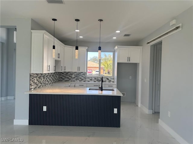 kitchen with decorative light fixtures, kitchen peninsula, and white cabinets