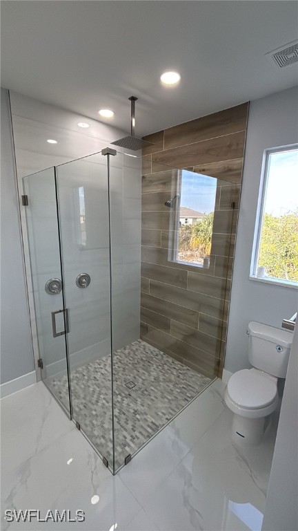 bathroom with a shower with door and toilet