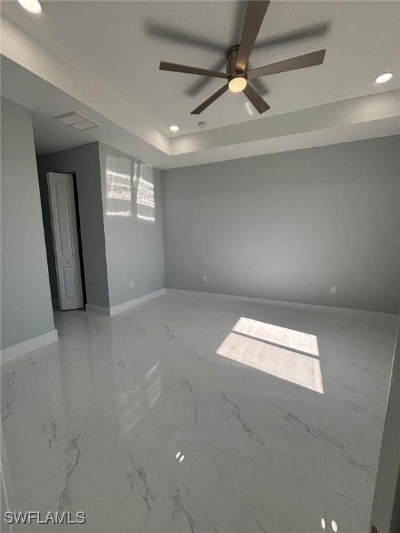 spare room with a tray ceiling and ceiling fan