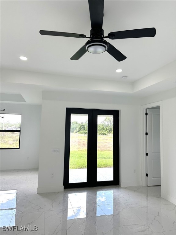 empty room with french doors, a wealth of natural light, and ceiling fan