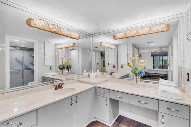 ensuite bathroom featuring an enclosed shower, wood finished floors, vanity, and ensuite bath