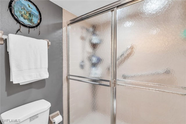 bathroom featuring a shower with shower door and toilet