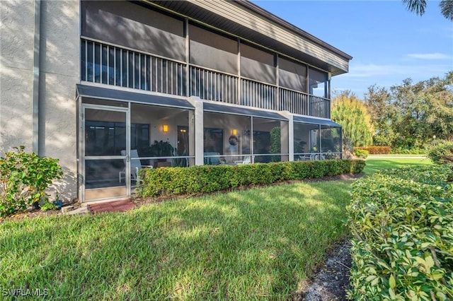 back of property with a lawn, stucco siding, and a sunroom