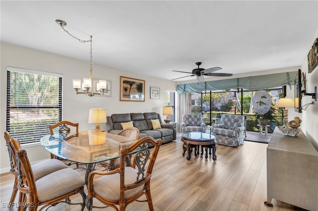 dining space with ceiling fan with notable chandelier, light hardwood / wood-style floors, and plenty of natural light