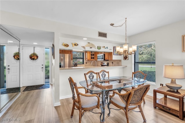 dining room with a notable chandelier, plenty of natural light, light hardwood / wood-style floors, and sink