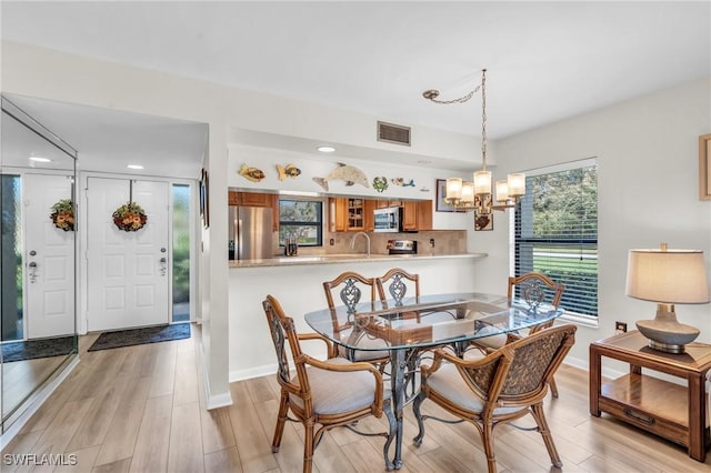 dining area with baseboards, visible vents, an inviting chandelier, and light wood finished floors