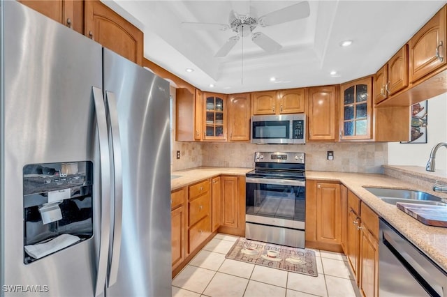 kitchen featuring ceiling fan, sink, stainless steel appliances, a raised ceiling, and light tile patterned floors