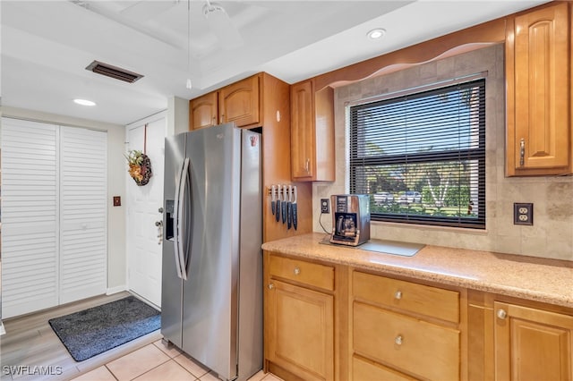 kitchen with ceiling fan, stainless steel refrigerator with ice dispenser, and a tray ceiling