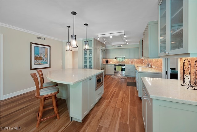 kitchen featuring light hardwood / wood-style floors, pendant lighting, crown molding, a center island, and track lighting