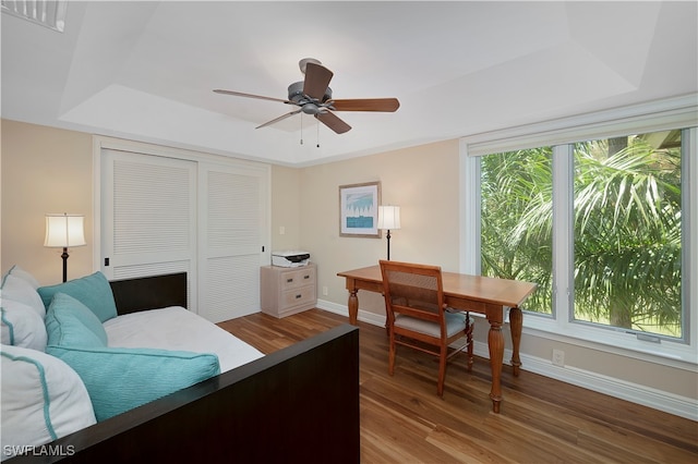 bedroom featuring a raised ceiling, hardwood / wood-style floors, and ceiling fan