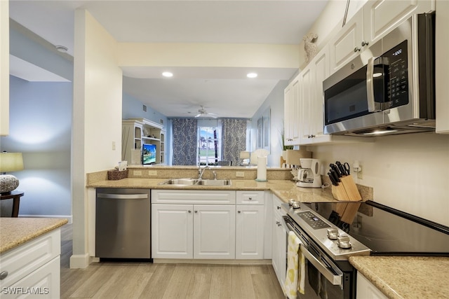 kitchen featuring white cabinets, appliances with stainless steel finishes, light wood-type flooring, and sink