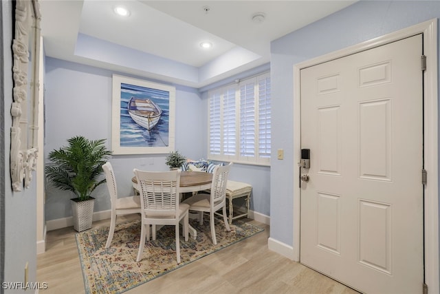 dining area featuring light hardwood / wood-style flooring and a tray ceiling