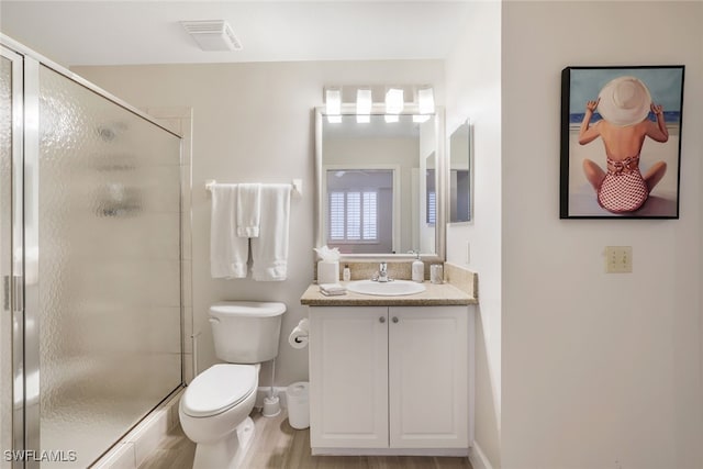 bathroom featuring wood-type flooring, vanity, toilet, and an enclosed shower