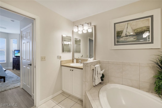 bathroom with vanity, tiled bath, and tile patterned flooring