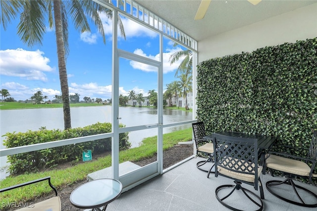 sunroom featuring a water view and ceiling fan