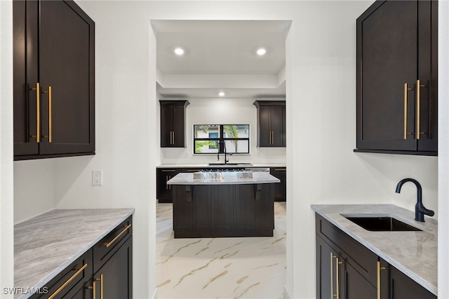 kitchen featuring dark brown cabinets, light stone countertops, sink, and a kitchen island