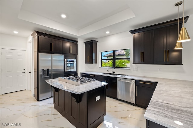 kitchen with pendant lighting, a tray ceiling, a breakfast bar, sink, and appliances with stainless steel finishes