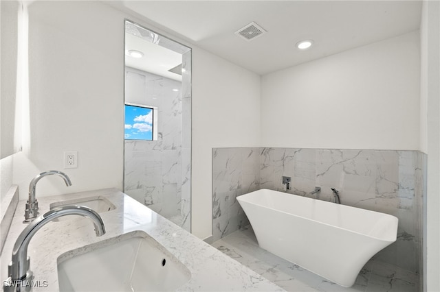 bathroom featuring vanity, tile walls, and a bath