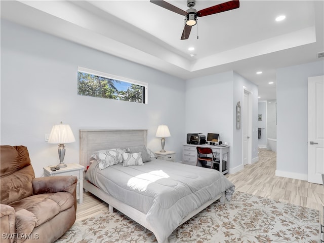 bedroom featuring ceiling fan, a raised ceiling, and light wood-type flooring