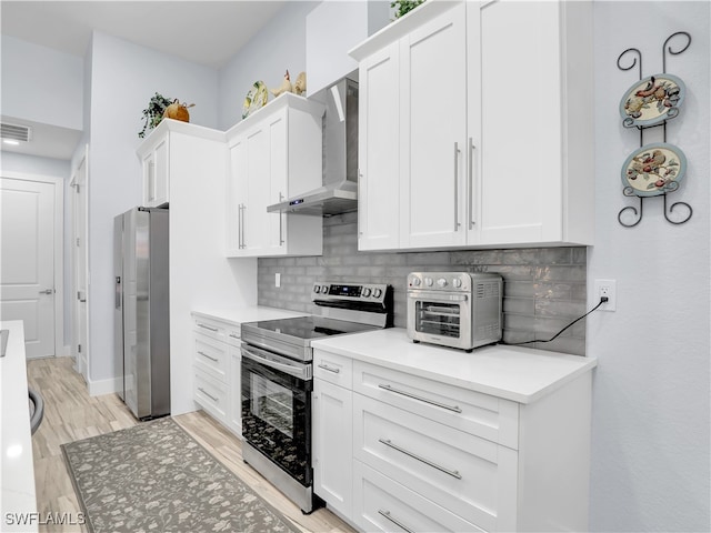 kitchen featuring wall chimney exhaust hood, white cabinetry, light hardwood / wood-style flooring, and stainless steel appliances