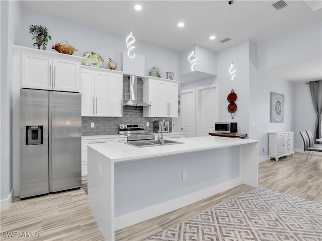 kitchen with wall chimney exhaust hood, white cabinetry, hanging light fixtures, and stainless steel appliances