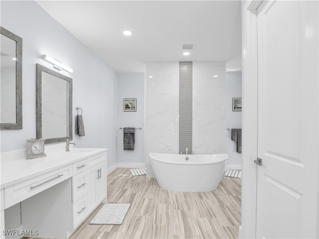 bathroom with vanity, wood-type flooring, and a bath