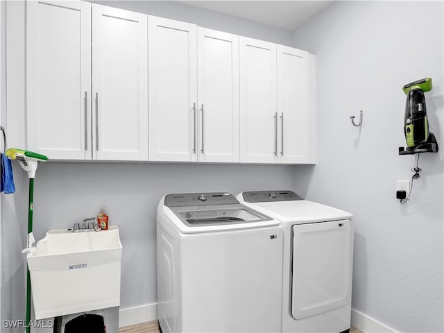 laundry area with sink, washer and dryer, and cabinets