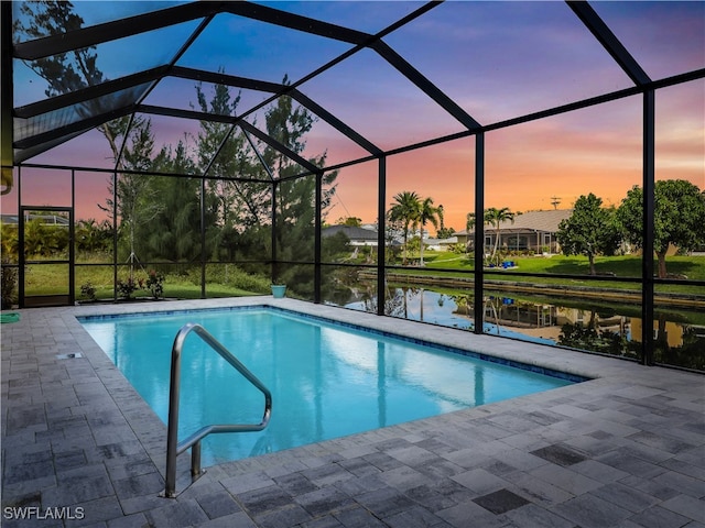 pool at dusk featuring a patio, a water view, and a lanai