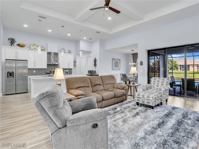 living room featuring beam ceiling, light hardwood / wood-style floors, and ceiling fan