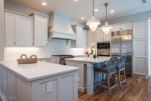 kitchen featuring built in appliances, custom range hood, dark hardwood / wood-style floors, and white cabinets