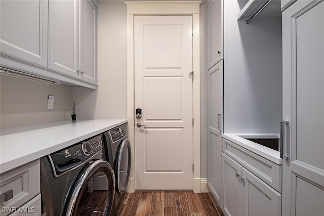 washroom featuring dark hardwood / wood-style flooring, washing machine and dryer, and cabinets