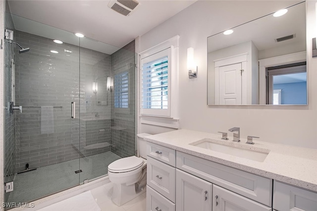 bathroom with vanity, toilet, and a shower with door