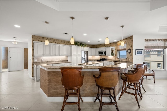 kitchen featuring white cabinets, sink, a breakfast bar area, a large island, and stainless steel appliances