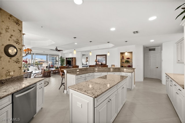 kitchen with a raised ceiling, hanging light fixtures, stainless steel dishwasher, ceiling fan, and a kitchen island