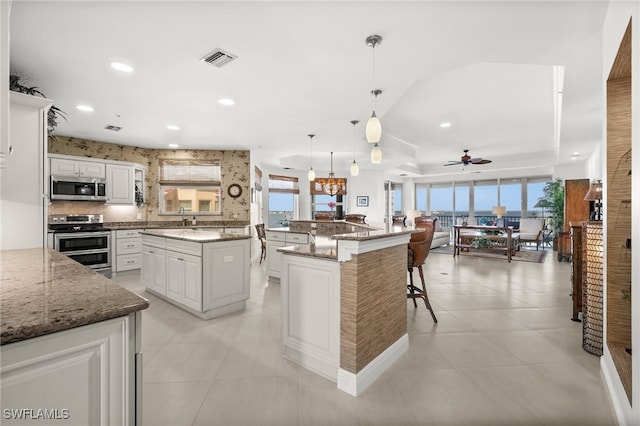 kitchen featuring white cabinets, a kitchen island, hanging light fixtures, and appliances with stainless steel finishes